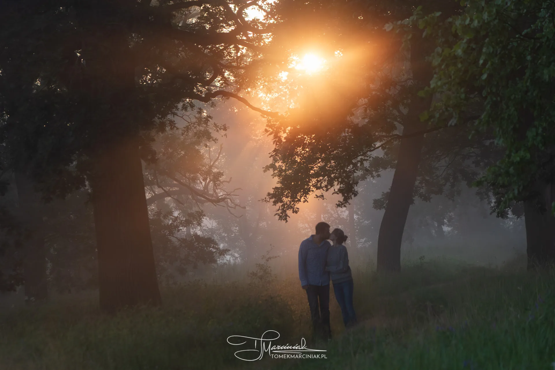 Zdjęcie pary spacerującej w&nbsp;lesie o&nbsp;wschodzie słońca
